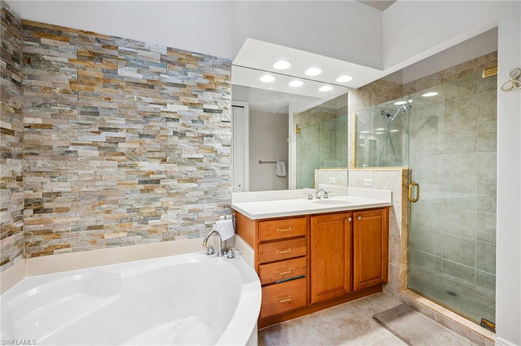 7859 Hawthorne Terrace, Unit 1504 Naples, FL 34113 - Photo 7 of 43 a bathroom with a double vanity sink mirror and bathtub