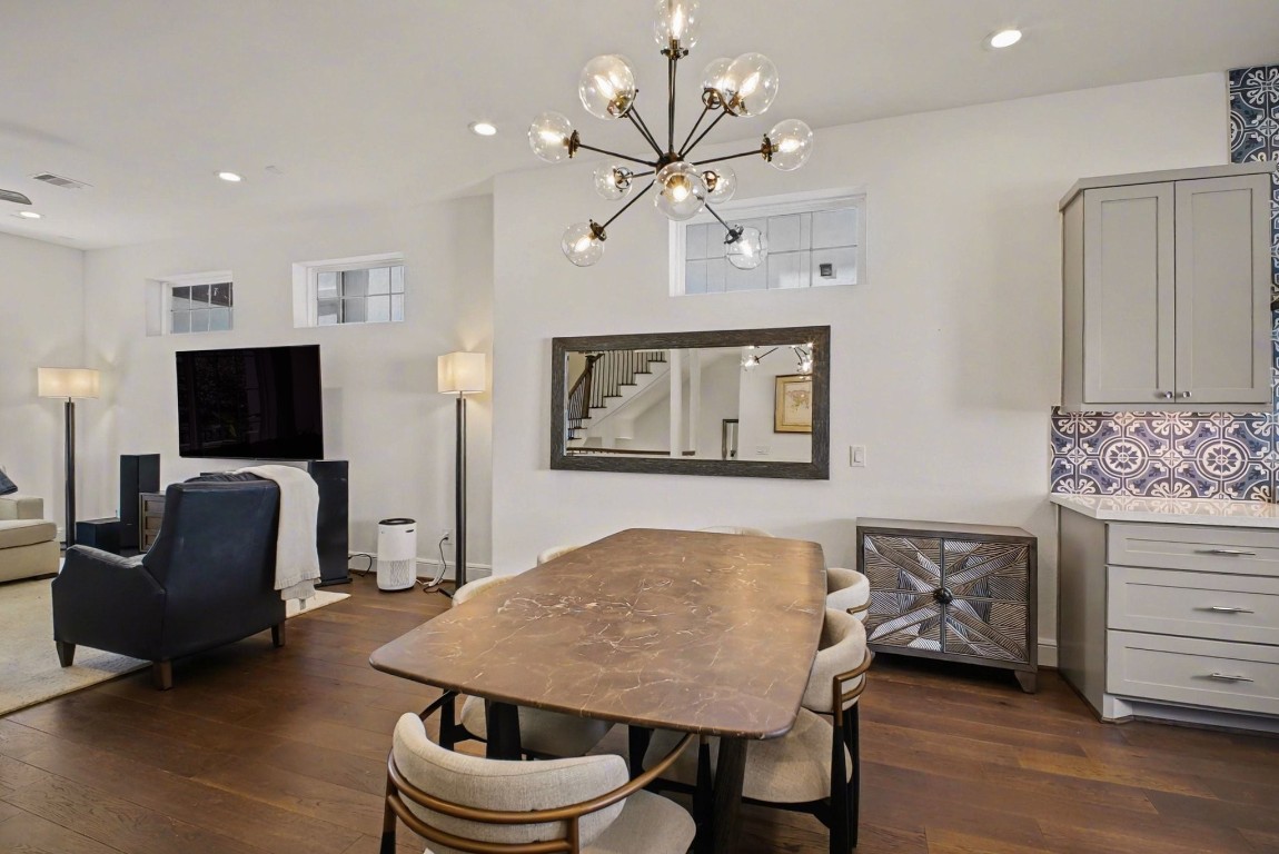3507 Ridgeway Valley Lane Houston, TX 77055 - Photo 11 of 50 This bright, open-concept living and dining area features hardwood floors, modern lighting, and a stylish accent wall with cabinets. The space is equipped with large windows, a sleek TV setup, and a chic dining table, offering a perfect blend of comfort and contemporary design.