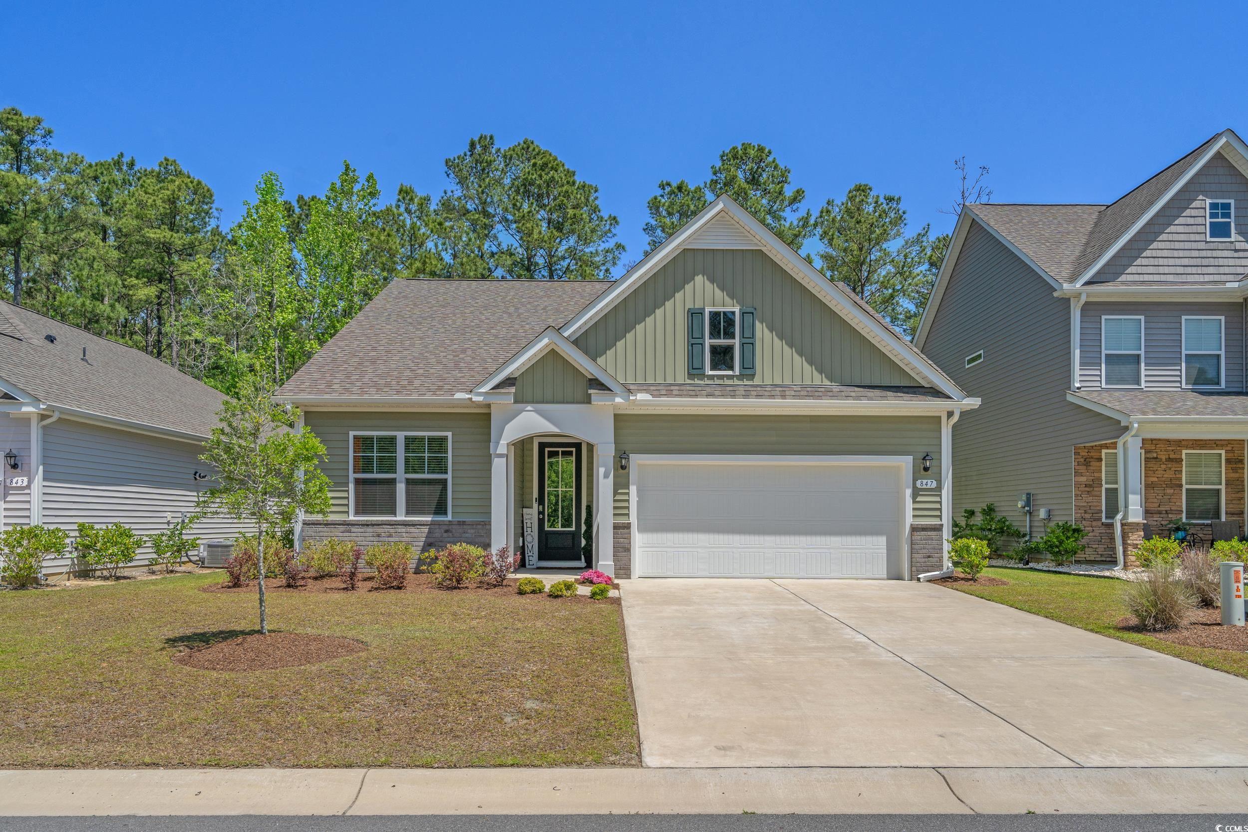 Craftsman-style home featuring board and batten siding, a front lawn, driveway, and a garage