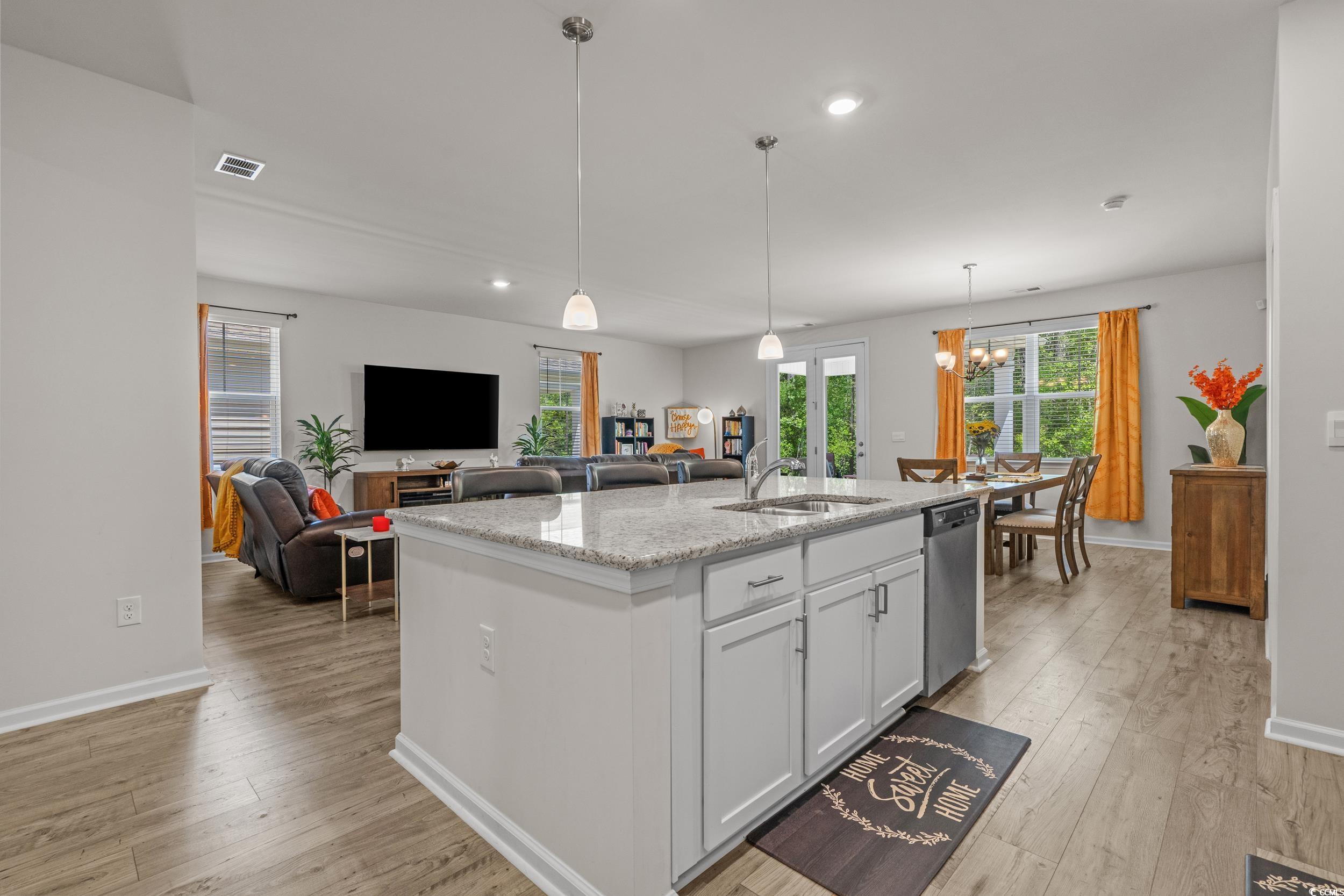 847 Flowering Br Avenue Little River, SC 29566 - Photo 10 of 30 Kitchen featuring white cabinetry, light stone countertops, decorative light fixtures, an island with sink, and light wood-style floors