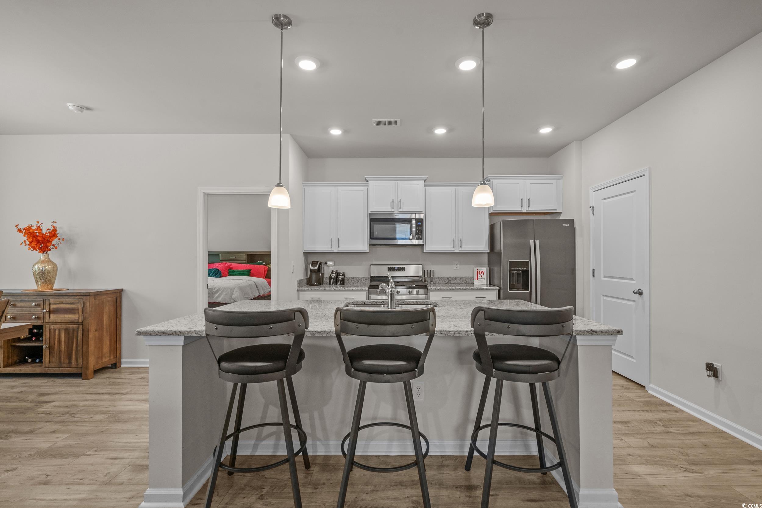 847 Flowering Br Avenue Little River, SC 29566 - Photo 8 of 30 Kitchen featuring white cabinets, a breakfast bar, pendant lighting, light stone countertops, and stainless steel appliances