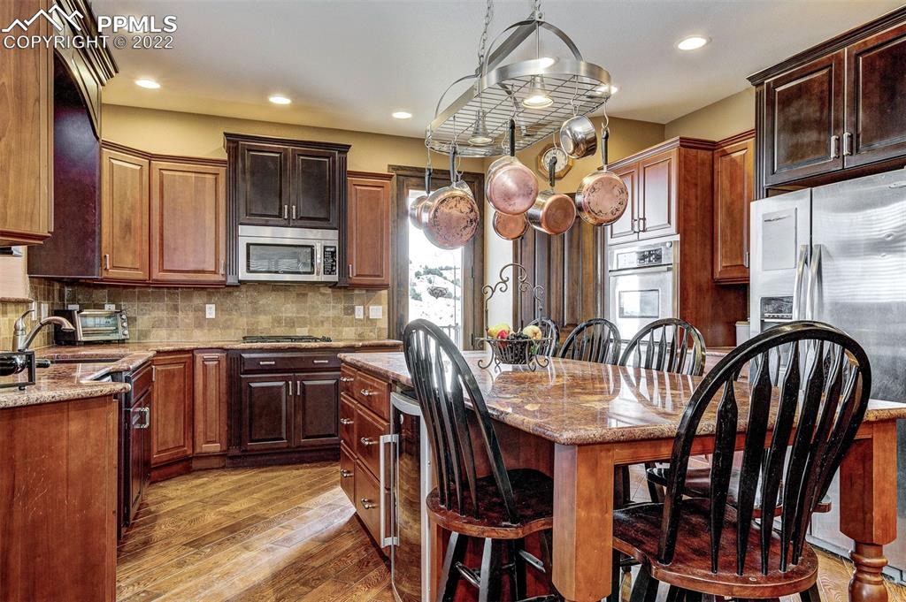 6453 Reno Road Pueblo, CO 81004 - Photo 15 of 36 a kitchen with stainless steel appliances granite countertop a stove a sink dishwasher a dining table and chairs with wooden floor