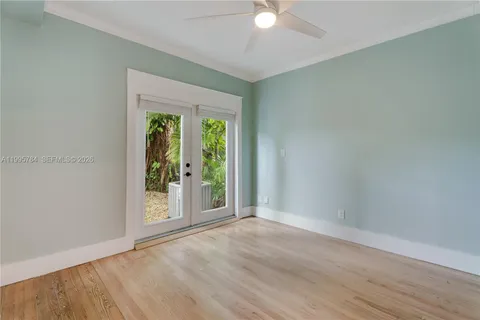 an empty room with wooden floor fan and window
