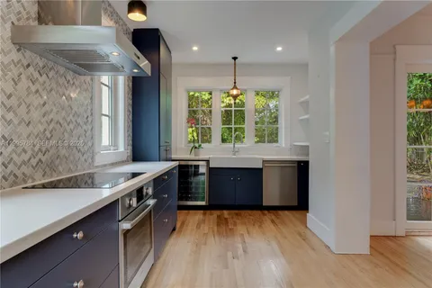 a kitchen with stainless steel appliances granite countertop a sink a stove and a wooden floors