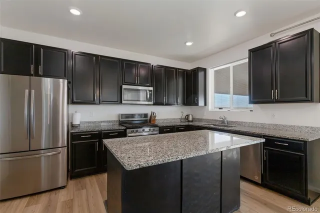 a kitchen with a sink a microwave a refrigerator and cabinets