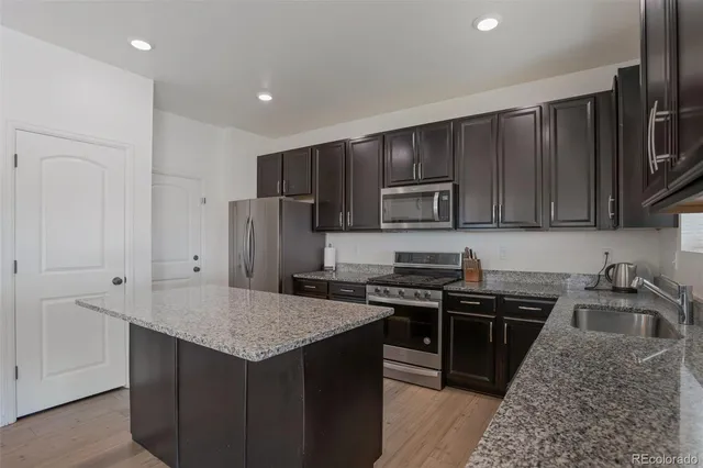 a kitchen with kitchen island granite countertop a sink stove and refrigerator