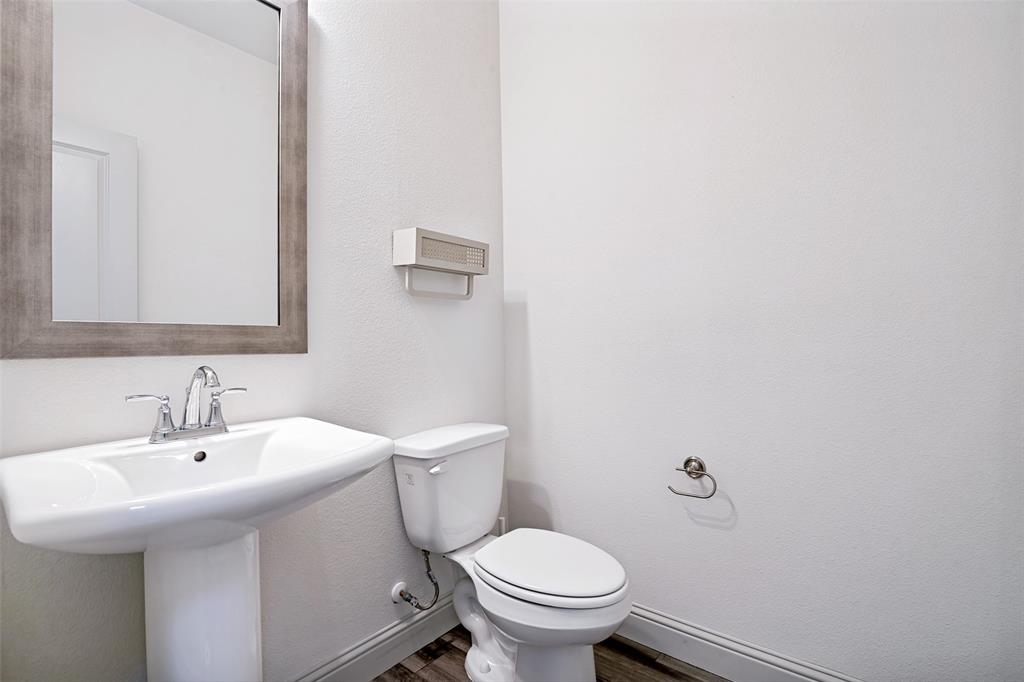1006 Emil Place Allen, TX 75013 - Photo 13 of 28 Pedestal sink with chrome faucet, framed mirror, and wood-finish flooring