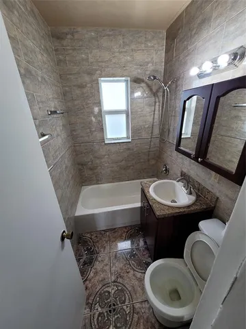 a bathroom with a sink a toilet a mirror and bathtub