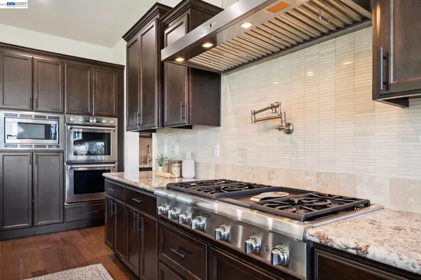 a kitchen with stainless steel appliances granite countertop a stove a sink and a refrigerator