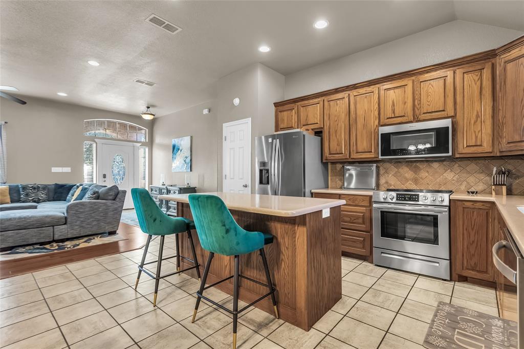 226 King George Road Ponder, TX 76259 - Photo 39 of 39 Kitchen featuring brown cabinetry, open floor plan, a center island, a breakfast bar area, and stainless steel appliances