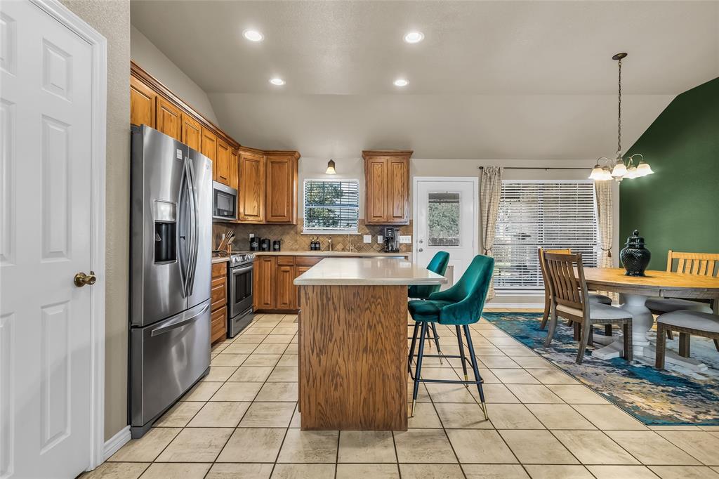 226 King George Road Ponder, TX 76259 - Photo 22 of 39 Kitchen with brown cabinets, tasteful backsplash, a kitchen breakfast bar, stainless steel appliances, and a kitchen island