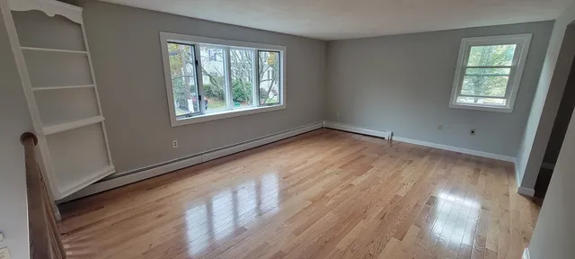 a view of an empty room with wooden floor and a window