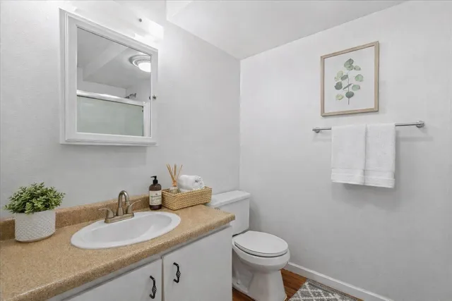 a bathroom with a granite countertop toilet sink and mirror