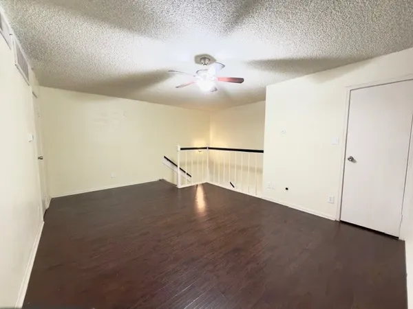an empty room with wooden floor and fan