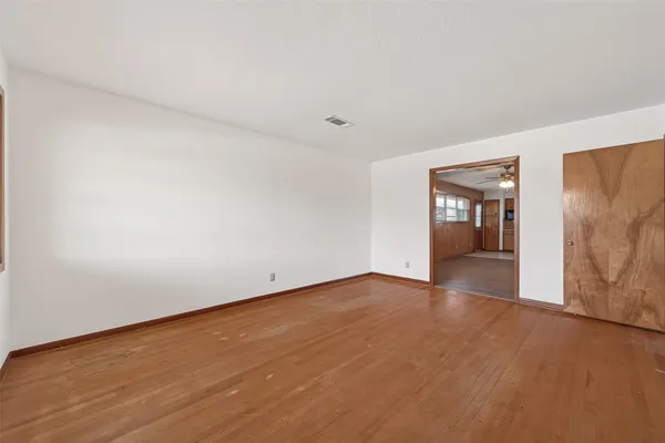 a view of an empty room with wooden floor and a window