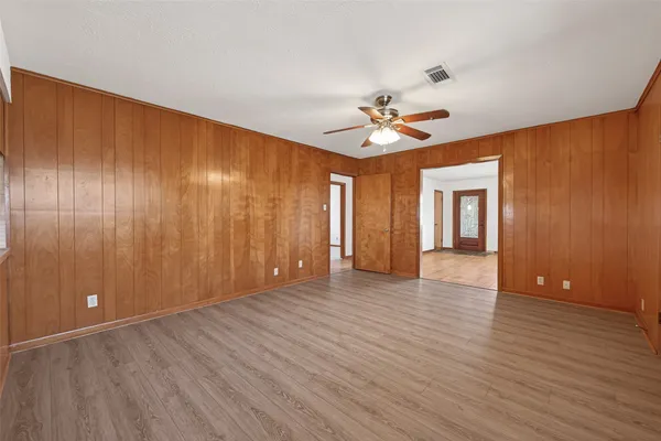 a view of an empty room with window and a ceiling fan