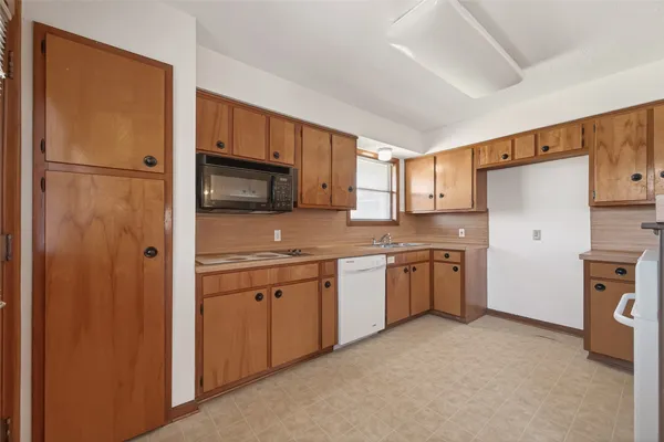 a kitchen with granite countertop a refrigerator stove top oven a sink and dishwasher
