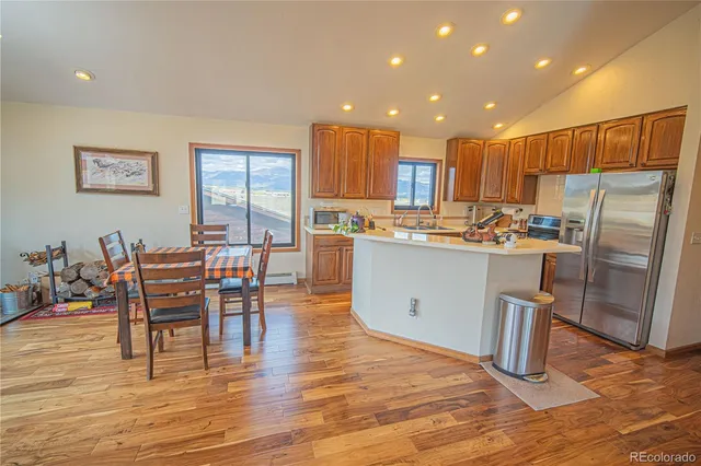 a kitchen with stainless steel appliances a dining table chairs and wooden floor