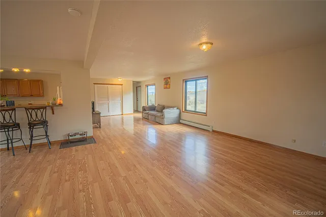 a view of a big room with wooden floor and a kitchen