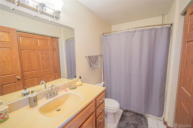 a bathroom with a sink a toilet a mirror and shower curtain