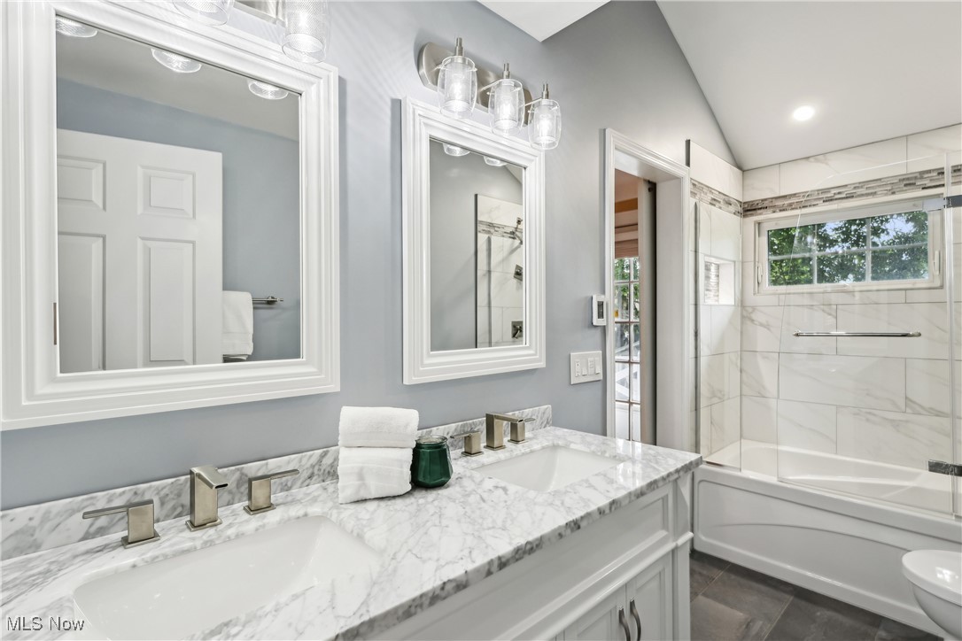 3295 Braemar Road Cleveland, OH 44120 - Photo 22 of 43 Bathroom featuring double vanity, toilet, lofted ceiling, and bathtub / shower combination with glass door. Bathroom features heated flooring.