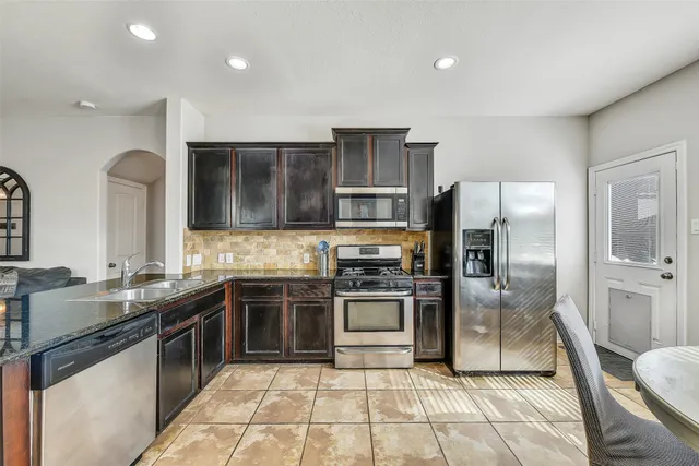 a kitchen with stainless steel appliances granite countertop a sink stove oven and refrigerator