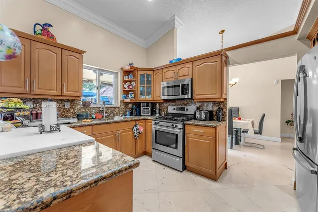 a kitchen with stainless steel appliances granite countertop a stove top oven a sink dishwasher a dining table and chairs with wooden floor