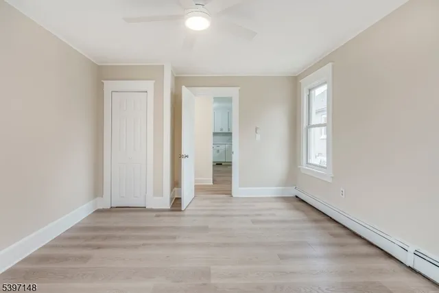 a view of an empty room with wooden floor and window