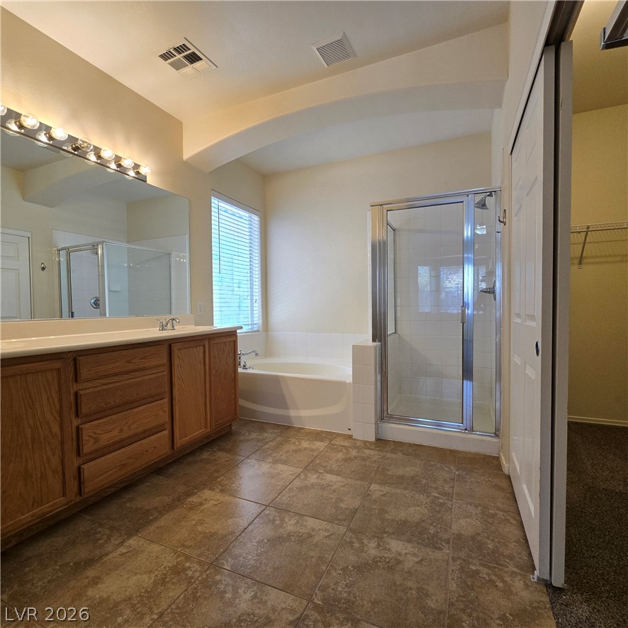 9234 Kingston Road Henderson, NV 89074 - Photo 26 of 38 A well-lit primary bathroom provides a spacious soaking tub, a separate shower, and dual sinks for convenience.