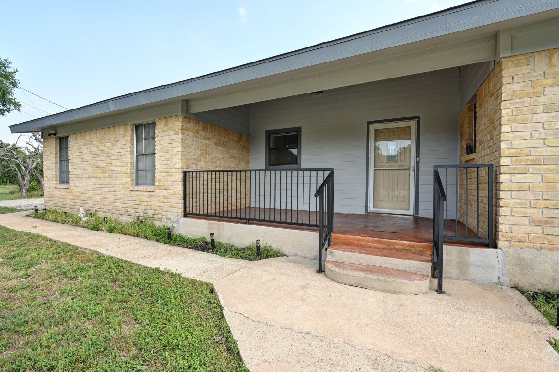 Doorway to property featuring covered porch and brick siding