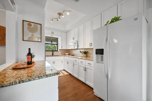 a kitchen with kitchen island granite countertop cabinets and white appliances