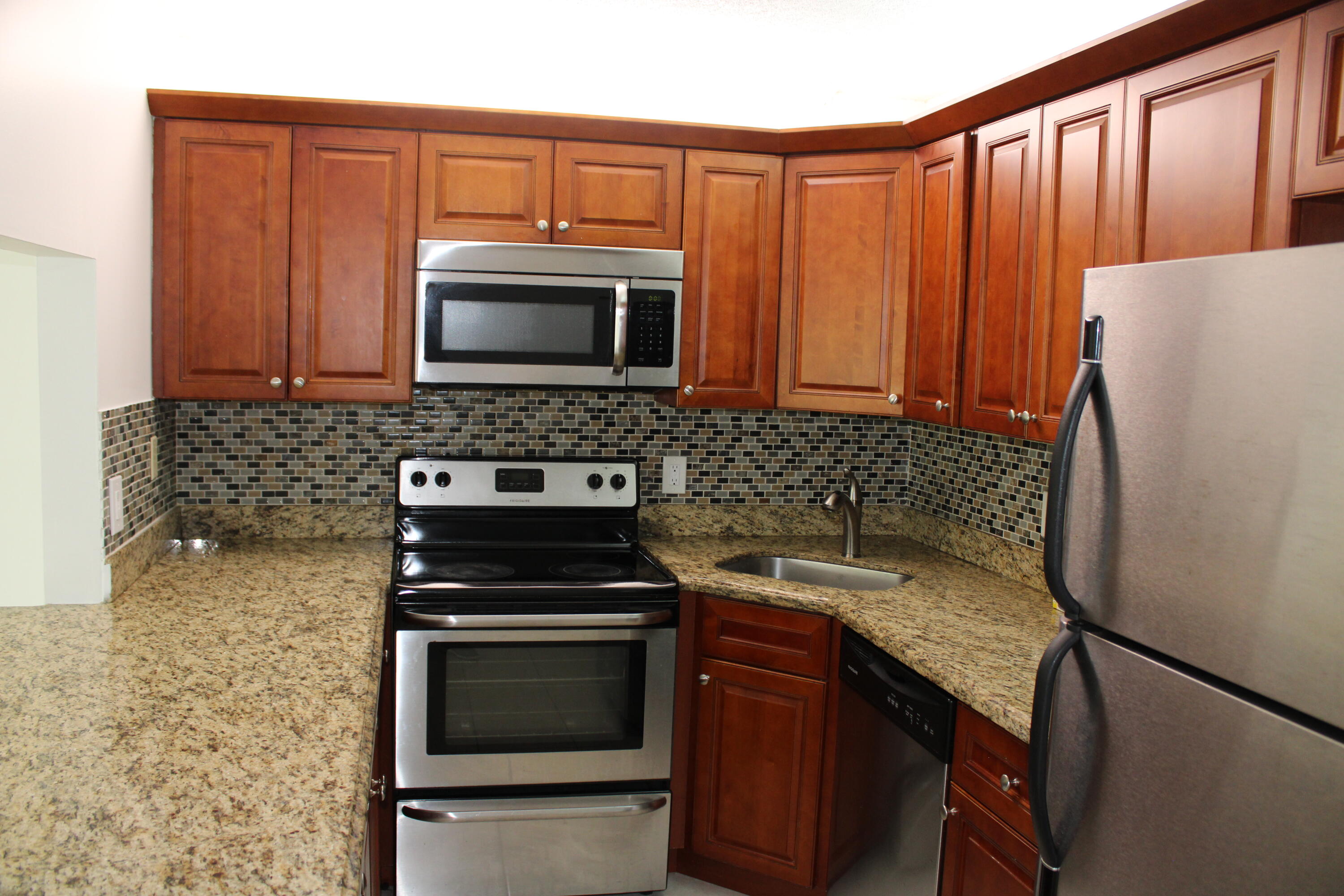 1006 Green Pine Boulevard, Unit H2 West Palm Beach, FL 33409 - Photo 3 of 12 a kitchen with granite countertop a stove sink and microwave