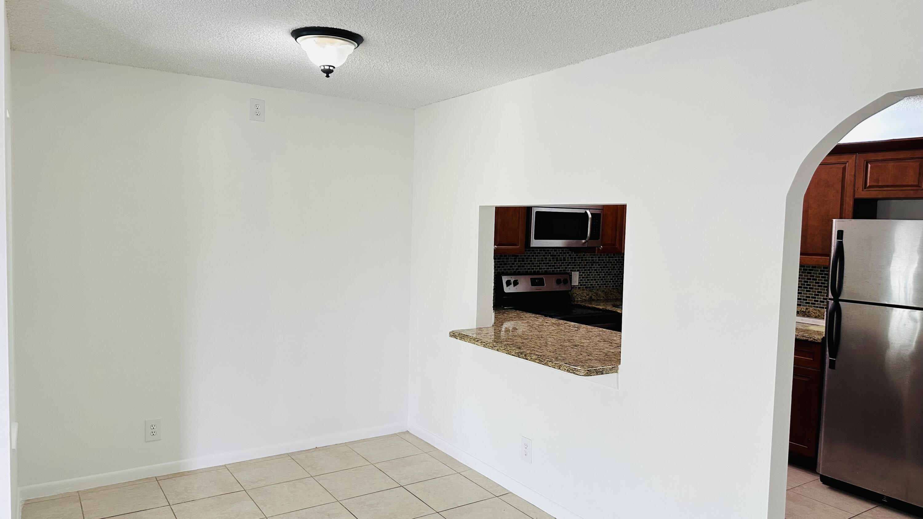 1006 Green Pine Boulevard, Unit H2 West Palm Beach, FL 33409 - Photo 4 of 12 a hallway with cabinets and a refrigerator