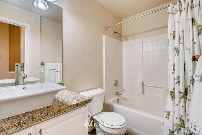 21624 9th Avenue Southeast, Unit D104 Bothell, WA 98021 - Photo 13 of 16 a bathroom with a granite countertop sink a toilet and shower
