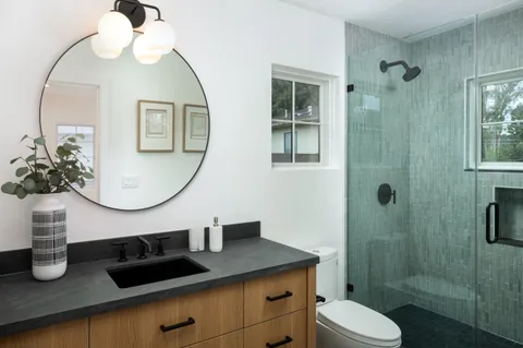 a bathroom with a granite countertop sink a toilet and shower