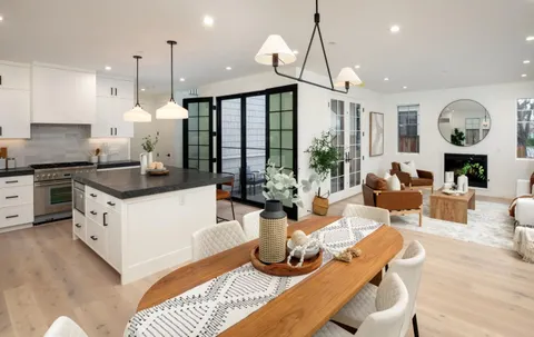 a kitchen with granite countertop a stove a sink a dining table and chairs with wooden floor