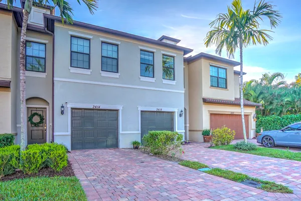 a front view of a house with yard and parking