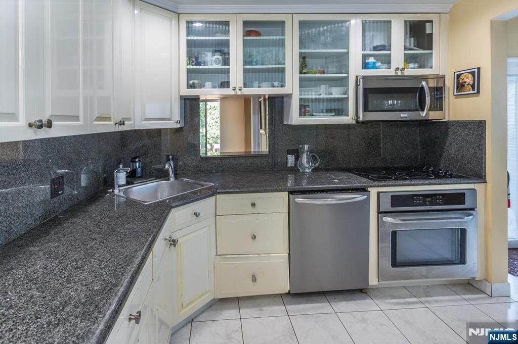 699 Kent Avenue Teaneck, NJ 07666 - Photo 15 of 31 a kitchen with granite countertop a stove sink and cabinets