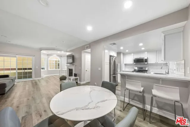 a view of kitchen with kitchen island stainless steel appliances sink refrigerator dining table and chairs