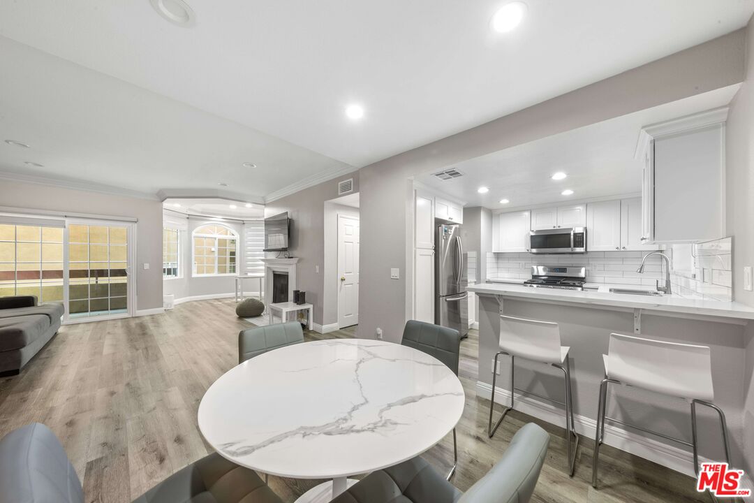 4301 Fulton Avenue, Unit 103 Sherman Oaks, CA 91423 - Photo 4 of 15 a view of kitchen with kitchen island stainless steel appliances sink refrigerator dining table and chairs