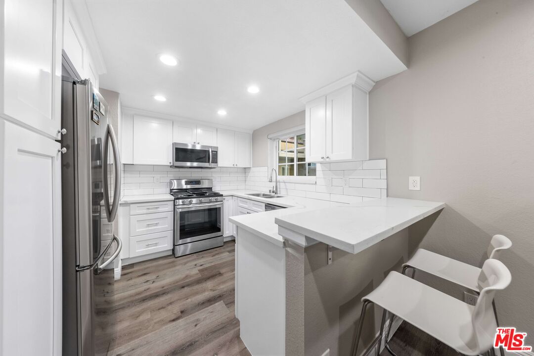 4301 Fulton Avenue, Unit 103 Sherman Oaks, CA 91423 - Photo 6 of 15 a kitchen with a stove a sink and a refrigerator