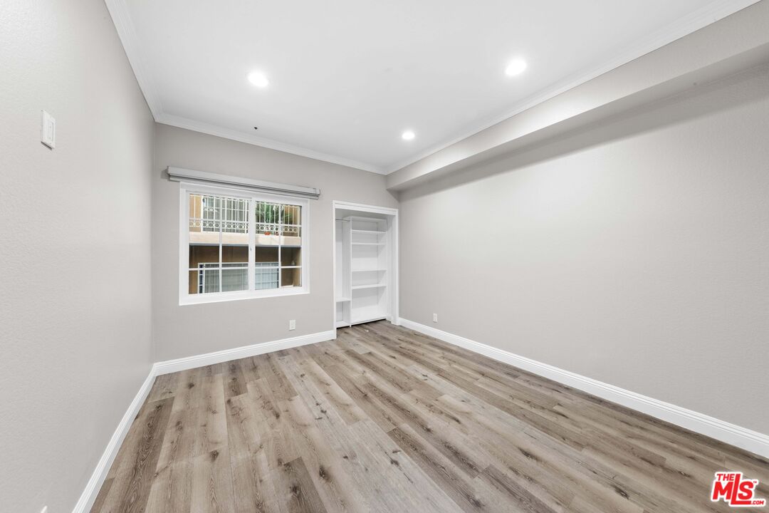 4301 Fulton Avenue, Unit 103 Sherman Oaks, CA 91423 - Photo 7 of 15 an empty room with wooden floor and windows