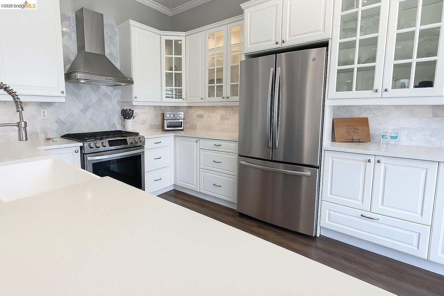 2072 Bridgeport Loop Discovery Bay, CA 94505 - Photo 11 of 26 Kitchen featuring decorative backsplash, stainless steel appliances, wall chimney range hood, white cabinetry, and dark wood-style flooring
