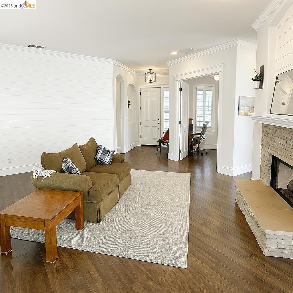 2072 Bridgeport Loop Discovery Bay, CA 94505 - Photo 5 of 26 Living room featuring a desk, dark wood-style floors, ornamental molding, arched walkways, and a fireplace