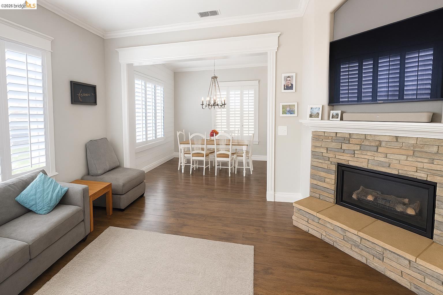2072 Bridgeport Loop Discovery Bay, CA 94505 - Photo 9 of 26 Living area with crown molding, a fireplace, dark wood-type flooring, and a chandelier