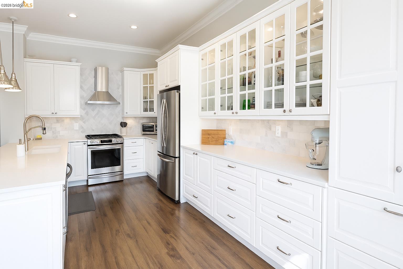 2072 Bridgeport Loop Discovery Bay, CA 94505 - Photo 10 of 26 Kitchen featuring decorative light fixtures, appliances with stainless steel finishes, white cabinets, decorative backsplash, and wall chimney exhaust hood