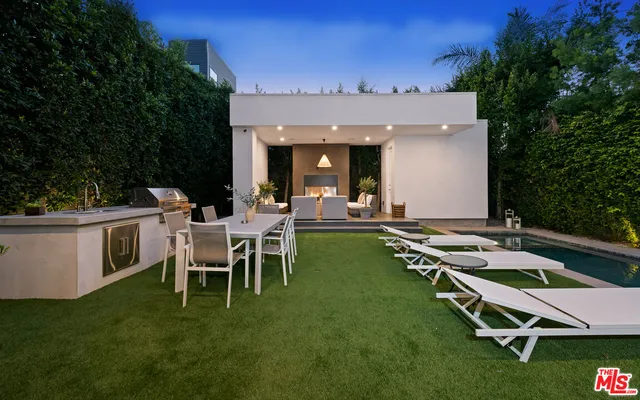 a view of a patio with table and chairs with plants and trees