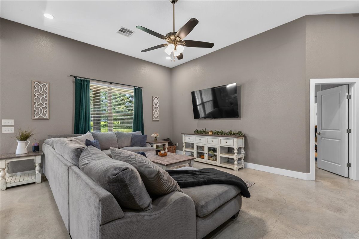 145 Cardinal Loop Paige, TX 78659 - Photo 10 of 40 Relax in this living area featuring high ceilings and concrete flooring, perfect for a modern aesthetic.