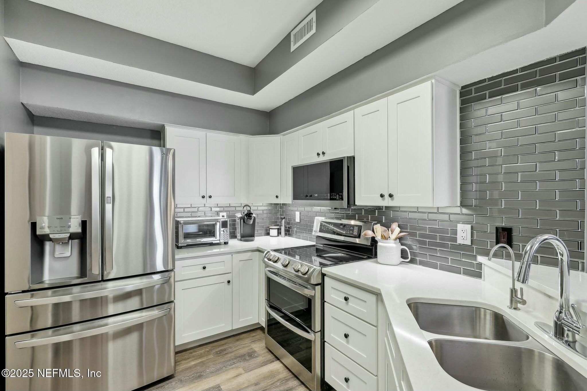 2102 Vista Cove Road St. Augustine, FL 32084 - Photo 5 of 40 a kitchen with white cabinets and stainless steel appliances