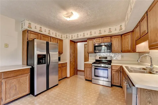 a kitchen with stainless steel appliances granite countertop a refrigerator a stove a sink and a microwave